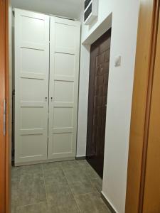 korytarz z białymi szafkami i drzwiami w obiekcie Apartman Tajna w mieście Sremčica