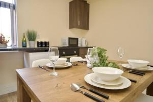 uma mesa de madeira com pratos, taças e copos de vinho em Matlock Studio 3 – Coventry em Coventry