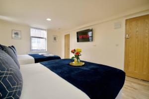 a hotel room with two beds and a vase of flowers at Matlock Studio 4 - Coventry in Coventry