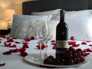 a bottle of wine and glasses on a bed with red roses at Hotel Boutique Doña Maria in Ocaña