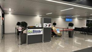 Sleeping Pods GoSleep - Inside of Warsaw Chopin Airport, non schengen restricted zone after passport control, near Gate 2N في وارسو: لوبي لمطار مع كونتر تسجيل الدخول