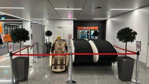 a baggage claim area in an airport with a red ribbon at Sleeping Pods GoSleep - Inside of Warsaw Chopin Airport, non schengen restricted zone after passport control, near Gate 2N in Warsaw