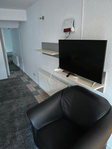 ein Wohnzimmer mit einem TV und einer schwarzen Couch in der Unterkunft 2 Zimmer Wohnung Bruchsal (Monteurzimmer) in Bruchsal