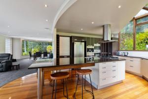 an open kitchen and living room with a counter and stools at Bayview Panorama - Paihia Holiday Home in Paihia +17 photos