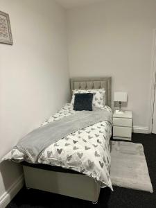 a white bedroom with a bed with a gray comforter at Dunedin Heights in London