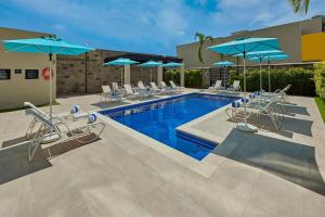 uma piscina com cadeiras e guarda-sóis e uma piscina em City Express by Marriott Tapachula em Tapachula