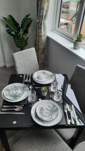 a table with plates and utensils on it at Stunning self-contained flat in house in Raynes Park