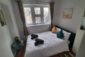 una camera da letto con un letto con due paia di scarpe sopra di Stunning self-contained flat in house a Raynes Park