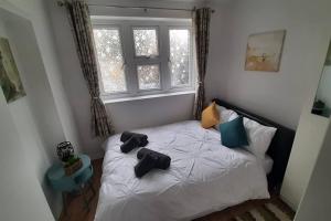 a bedroom with a bed with two pairs of shoes on it at Stunning self-contained flat in house in Raynes Park