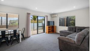 un soggiorno con divano e tavolo di Hibiscus Hideaway - Orewa Beach Holiday Home a Orewa