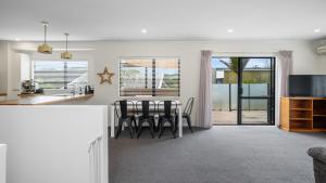 a kitchen and living room with a table and chairs at Hibiscus Hideaway - Orewa Beach Holiday Home in Orewa