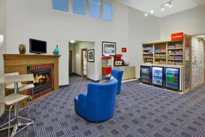 a waiting room with blue chairs and a fireplace at TownePlace Suites by Marriott Brookfield in Brookfield