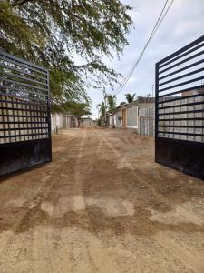 an empty dirt road with a gate and trees at La casa de Joan in Máncora