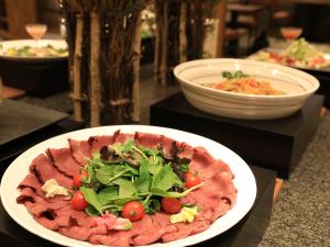 un plato de comida con una ensalada en una mesa en Hotel Taisetsu Onsen&Canyon Resort, en Kamikawa
