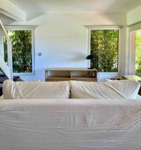 a bedroom with a large white bed with two windows at Duplex al Golf Sierra de los Padres in Sierra de los Padres +25 photos