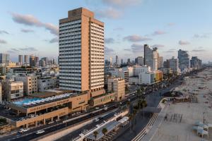 a tall building in the middle of a city at Sheraton Grand Tel Aviv in Tel Aviv