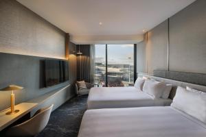 a hotel room with two beds and a tv at Pullman Auckland Airport in Auckland