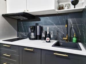 a kitchen counter with a sink and a bottle of wine at CLASSY APARTMENTS - Gdynia - Na Wzgórzu Deluxe in Gdynia