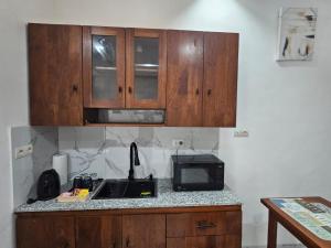 une cuisine avec des placards en bois et un comptoir avec un four micro-ondes dans l'établissement Studio Le Cosi, Cotonou, à Cotonou