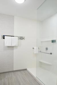 uma casa de banho branca com um chuveiro e uma porta de vidro em Residence Inn St. Petersburg Tierra Verde em Tierra Verde