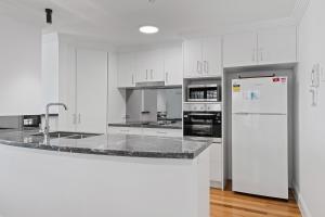 バイロンベイにあるWaterview Beachside Apartment - Palms 2の白いキャビネットと白い冷蔵庫のあるキッチン