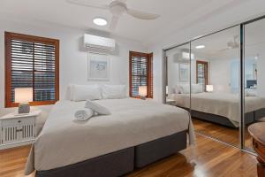 バイロンベイにあるWaterview Beachside Apartment - Palms 2の白いベッドルーム(ベッド2台、鏡付)