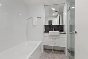 バイロンベイにあるWaterview Beachside Apartment - Palms 2の浴槽と洗面台のある白いバスルーム +8枚の写真