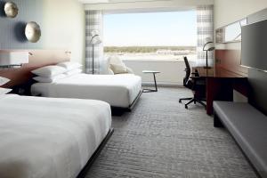 a hotel room with two beds and a desk at Marriott Montreal Airport In-Terminal Hotel in Dorval