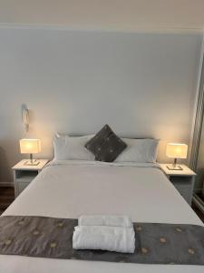 a large white bed with two lamps on two tables at Paxsafe Sydney Hyde Park Private Apartments in Sydney