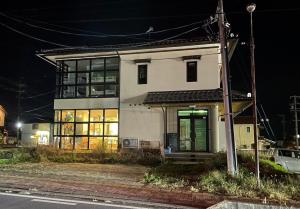een wit huis met een groene deur in een straat bij 小布施のあたり in Obuse