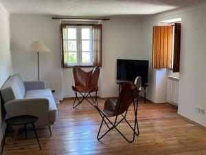 ein Wohnzimmer mit einem Sofa, Stühlen und einem TV in der Unterkunft Casa do Reguengo (New!) in Castelo de Vide