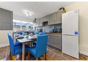 uma cozinha com uma mesa, cadeiras azuis e um frigorífico em Stunning Family Home - Sleeps 11 em Londres