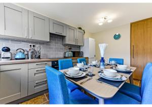 una cucina con tavolo da pranzo e sedie blu di Stunning Family Home - Sleeps 11 a Londra