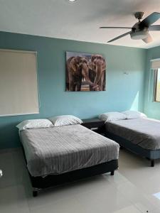 Dos camas en un dormitorio con una pintura de dos elefantes en Hermosa CASA con ALBERCA PRIVADA en Cholul
