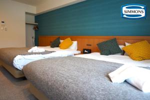 大阪市にあるApartment Hotel 11 Namba Minami Shin-Imamiyaのベッド2台が備わる客室で、壁に看板が付いています。
