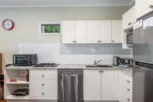 a kitchen with white cabinets and stainless steel appliances at Cockatoo Hideaway- Cabin in Montville