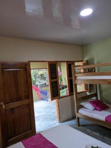 a room with three bunk beds and a door at Sierra Kay Hostel in Guachaca