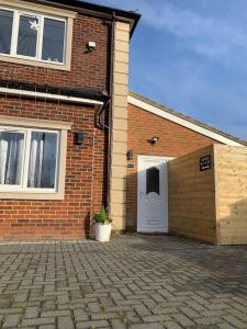 a brick building with a garage and a white door at Apartment C, a one bedroom Flat in south London in Carshalton