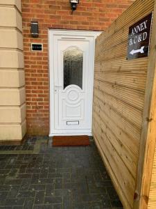 a white door in a brick building with a sign at Apartment C, a one bedroom Flat in south London in Carshalton