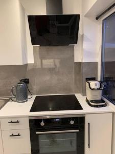 a kitchen with a stove top and a microwave at Apartment C, a one bedroom Flat in south London in Carshalton