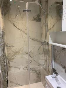 a shower with a glass door in a bathroom at Apartment C, a one bedroom Flat in south London in Carshalton