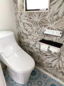 a bathroom with a toilet and a flowery wallpaper at Pier39 Uchiumi Cozy house located in front of the sea and harbor! in Miyazaki