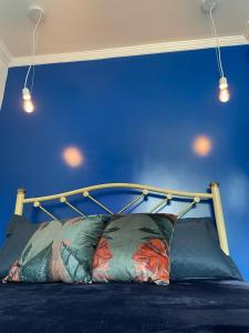 a bed with a blue wall with lights above it at Pedacinho do céu in Cabo Frio
