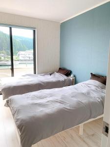 two beds in a room with a large window at Pier39 Uchiumi Cozy house located in front of the sea and harbor! in Miyazaki