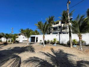 a white building with palm trees in front of it at Apartamento na praia da tabuba com vista mar in Caucaia