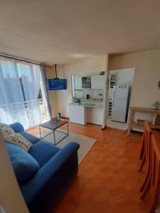 a living room with a blue couch and a kitchen at La serena a pasos de la playa, sector 4 Esquina, lindo y acogedor departamento in La Serena