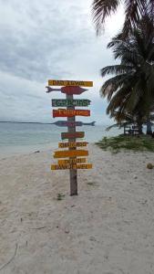 a directional sign on a beach with the ocean at Isla diablo cabañas en la orilla del mar baño compartido in Cagantupo