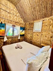 a bedroom with a bed and a straw roof at Marahuyo Siargao in Catangnan