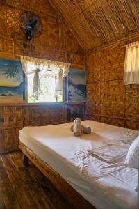 a bedroom with a bed with a teddy bear on it at Marahuyo Siargao in Catangnan