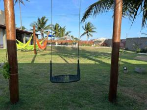 a hammock hanging between two palm trees in a park at Paraíso PÉ NA AREIA no coração do litoral norte in Ilhéus